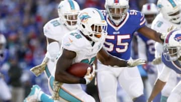 Nov 8, 2015; Orchard Park, NY, USA; Miami Dolphins running back Lamar Miller (26) runs with the ball as Buffalo Bills defensive end Jerry Hughes (55) pursues during the second half at Ralph Wilson Stadium. Mandatory Credit: Kevin Hoffman-USA TODAY Sports