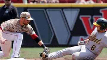 Jun 12, 2016; Cincinnati, OH, USA; Cincinnati Reds shortstop Zack Cozart (L) tags out Oakland Athletics second baseman Jed Lowrie (8) during the seventh inning at Great American Ball Park. The Athletics won 6-1. Mandatory Credit: David Kohl-USA TODAY Sports