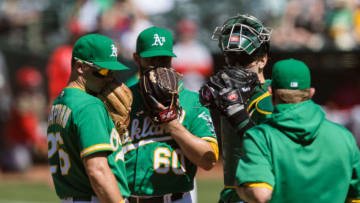 May 30, 2021; Oakland, California, USA; Oakland Athletics pitching coach Scott Emerson (right) approaches the mound to talk to relief pitcher Cam Bedrosian (60) as third baseman Matt Chapman (26) and catcher Sean Murphy (second from right) look on during the eighth inning against the Los Angeles Angels at RingCentral Coliseum. Mandatory Credit: John Hefti-USA TODAY Sports