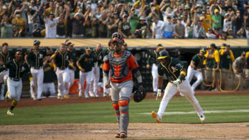 Sep 25, 2021; Oakland, California, USA; Oakland Athletics shortstop Elvis Andrus (right) scores the winning run against the Houston Astros during the ninth inning at RingCentral Coliseum. Andrus scored from first on a double by Oakland center fielder Starling Marte, but injured his leg on the play and had to be helped from the field. Mandatory Credit: D. Ross Cameron-USA TODAY Sports