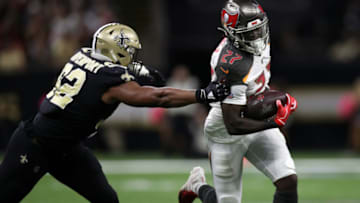 NEW ORLEANS, LOUISIANA - OCTOBER 06: Ronald Jones #27 of the Tampa Bay Buccaneers avoids a tackle by Marcus Davenport #92 of the New Orleans Saints at Mercedes Benz Superdome on October 06, 2019 in New Orleans, Louisiana. (Photo by Chris Graythen/Getty Images)