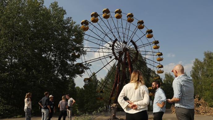 PRIPYAT, UKRAINE - AUGUST 19: Tourists look at an abandoned ferris wheel in the ghost town of Pripyat not far from the Chernobyl nuclear power plant on August 19, 2017 in Pripyat, Ukraine. On April 26, 1986 reactor number four exploded after a safety test went wrong, spreading radiation over thousands of square kilometers in different directions. Ukraine and Belarus are still challenged by the consequences of the accident, with huge swaths of territory that remain uninhabitable as well as ongoing health effects for their populations. (Photo by Sean Gallup/Getty Images) PRIPYAT, UKRAINE - AUGUST 19: Tourists look at an abandoned ferris wheel in the ghost town of Pripyat not far from the Chernobyl nuclear power plant on August 19, 2017 in Pripyat, Ukraine. On April 26, 1986 reactor number four exploded after a safety test went wrong, spreading radiation over thousands of square kilometers in different directions. Ukraine and Belarus are still challenged by the consequences of the accident, with huge swaths of territory that remain uninhabitable as well as ongoing health effects for their populations. (Photo by Sean Gallup/Getty Images)