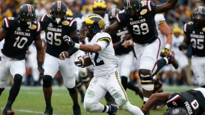 TAMPA, FL - JANUARY 1: Running back Chris Evans #12 of the Michigan Wolverines slips a tackle by defensive lineman D.J. Wonnum #8 of the South Carolina Gamecocks during a carry in the first quarter of the Outback Bowl NCAA college football game on January 1, 2018 at Raymond James Stadium in Tampa, Florida. (Photo by Brian Blanco/Getty Images)