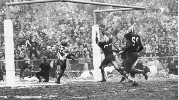 American football player Jim Brown (#32) of the Cleveland Browns keeps his eyes on the ball as Ray Nitschke (#66) of the Green Bay Packers reaches up to intercept the ball during the NFL Championship game on a very muddy field, Green Bay, Wisconson, January 2, 1966. The Packers went on to win the game. (Photo by Robert Riger/Getty Images)