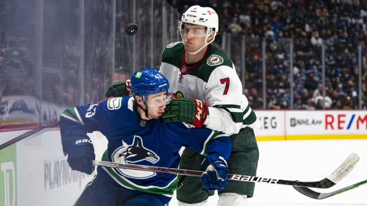 VANCOUVER, BC – OCTOBER 26: Quinn Hughes #43 of the Vancouver Canucks and Nico Sturm #7 of the Minnesota Wild battle for the loose puck along the boards during the first period of NHL action on October, 26, 2021 at Rogers Arena in Vancouver, British Columbia, Canada. (Photo by Rich Lam/Getty Images)