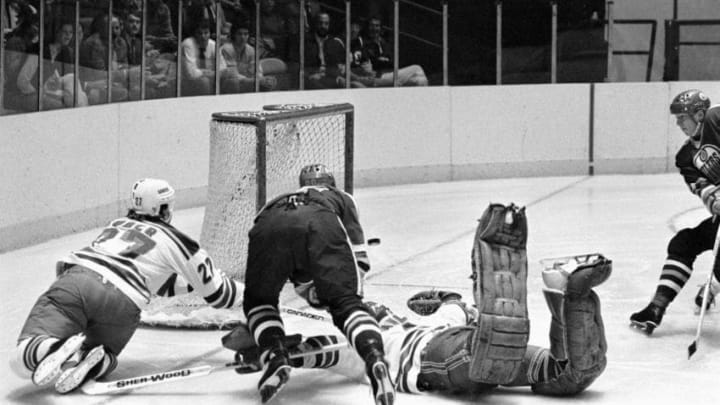 (Original Caption) All eyes are on the puck as Oilers' Wayne Gretzky (9) flips the puck into the net as he falls over Ranger goalie Glen Hanlon and scores the Oilers' first goal in 1st period action at Madison Square Garden 12/14.