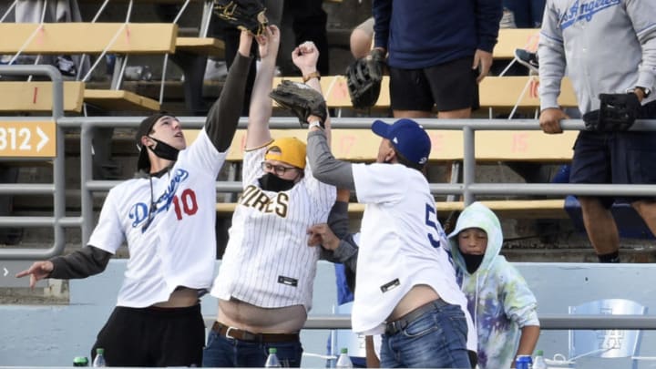 Apr 25, 2021; Los Angeles, California, USA; A San Diego Padres fan reaches up to vie for a home run hit by Los Angeles Dodgers second baseman Chris Taylor (3) between two Dodger fans during the sixth inning at Dodger Stadium. Mandatory Credit: Kelvin Kuo-USA TODAY Sports