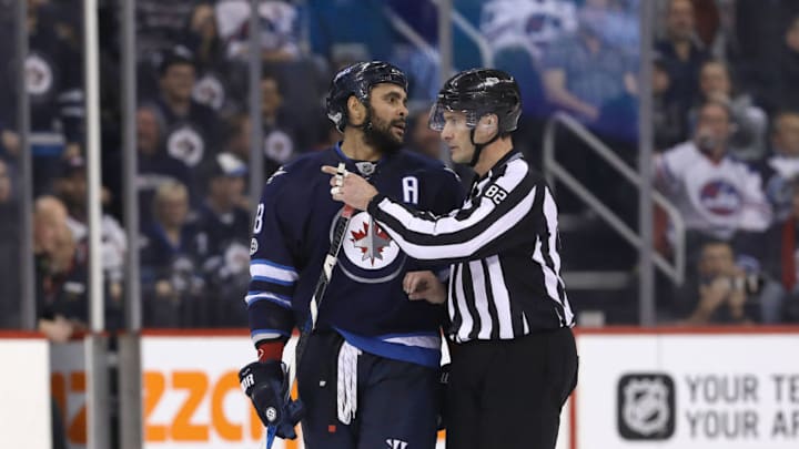 WINNIPEG, MANITOBA - MARCH 11: A linesman directs Dustin Byfuglien