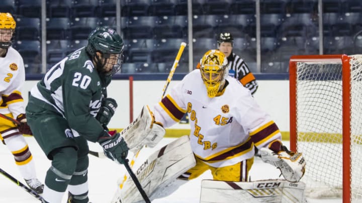 Mar 14, 2021; South Bend, Indiana, USA; Michigan State's Josh Nodler (20) shoots at Minnesota's Jack LaFontaine (45) at the Compton Family Ice Arena. Mandatory Credit: Michael Caterina/South Bend Tribune-USA TODAY NETWORK