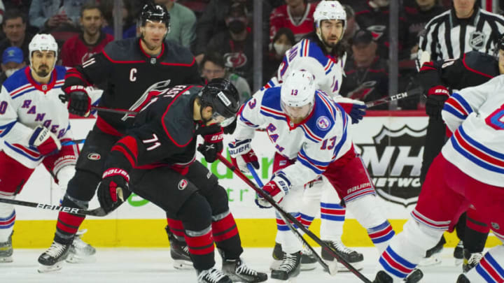 Mar 20, 2022; Raleigh, North Carolina, USA; New York Rangers left wing Alexis Lafrenière (13) and Carolina Hurricanes right wing Jesper Fast (71) battle over the loose puck during the first period at PNC Arena. Mandatory Credit: James Guillory-USA TODAY Sports