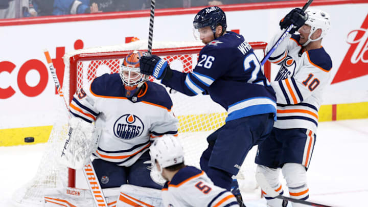 Feb 19, 2022; Winnipeg, Manitoba, CAN; Edmonton Oilers goaltender Mikko Koskinen (19) and Winnipeg Jets right wing Blake Wheeler (26) eye the puck in the third period at Canada Life Centre. Mandatory Credit: James Carey Lauder-USA TODAY Sports