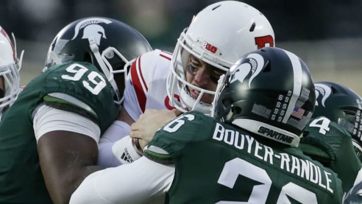 EAST LANSING, MI - NOVEMBER 24: Quarterback Giovanni Rescigno #17 of the Rutgers Scarlet Knights is wrapped up by defensive tackle Raequan Williams #99 of the Michigan State Spartans and linebacker Brandon Bouyer-Randle #26 of the Michigan State Spartans during the first half at Spartan Stadium on November 24, 2018 in East Lansing, Michigan. (Photo by Duane Burleson/Getty Images)