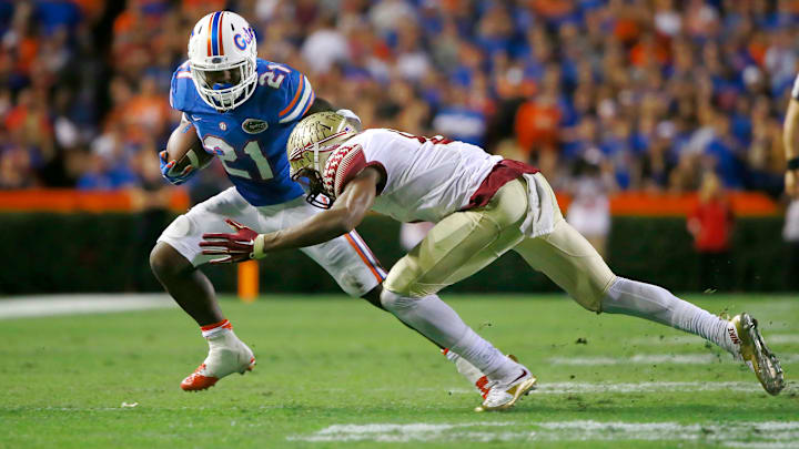 Nov 28, 2015; Gainesville, FL, USA; Florida Gators running back Kelvin Taylor (21) runs with the ball as Florida State Seminoles defensive end Josh Sweat (9) tackles him during the first quarter at Ben Hill Griffin Stadium. Mandatory Credit: Kim Klement-USA TODAY Sports