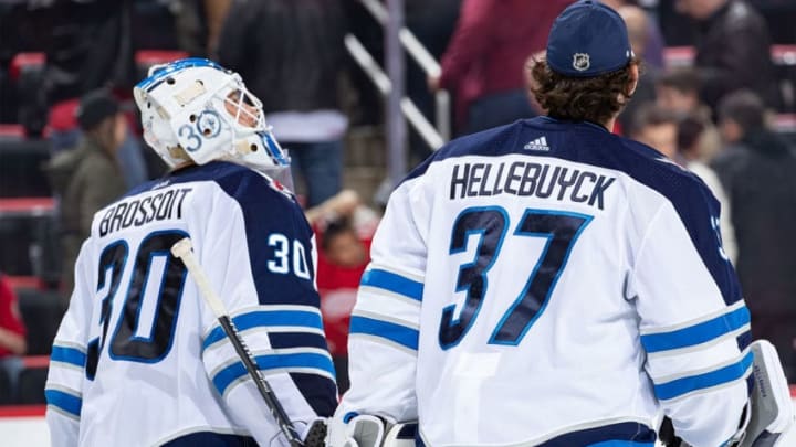 DETROIT, MI - OCTOBER 26: Laurent Brossoit #30 of the Winnipeg Jets skates off the ice with teammate Connor Hellebuyck #37 during an NHL game at Little Caesars Arena on October 26, 2018 in Detroit, Michigan. The Jets defeated the Wings 2-1. (Photo by Dave Reginek/NHLI via Getty Images)