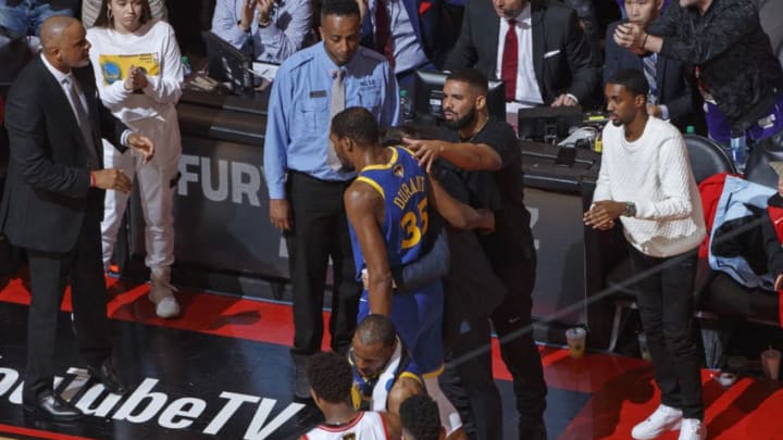 TORONTO, CANADA - JUNE 10: Rapper, Drake talks to Kevin Durant #35 of the Golden State Warriors after sustaining an injury during Game Five of the NBA Finals against the Toronto Raptors on June 10, 2019 at Scotiabank Arena in Toronto, Ontario, Canada. NOTE TO USER: User expressly acknowledges and agrees that, by downloading and/or using this photograph, user is consenting to the terms and conditions of the Getty Images License Agreement. Mandatory Copyright Notice: Copyright 2019 NBAE (Photo by Mark Blinch/NBAE via Getty Images)
