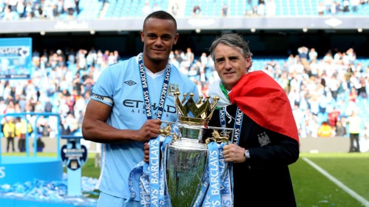 MANCHESTER, ENGLAND - MAY 13: Vincent Kompany the captain of Manchester City and Roberto Mancini the manager of Manchester City pose with the trophy following the Barclays Premier League match between Manchester City and Queens Park Rangers at the Etihad Stadium on May 13, 2012 in Manchester, England. (Photo by Alex Livesey/Getty Images)