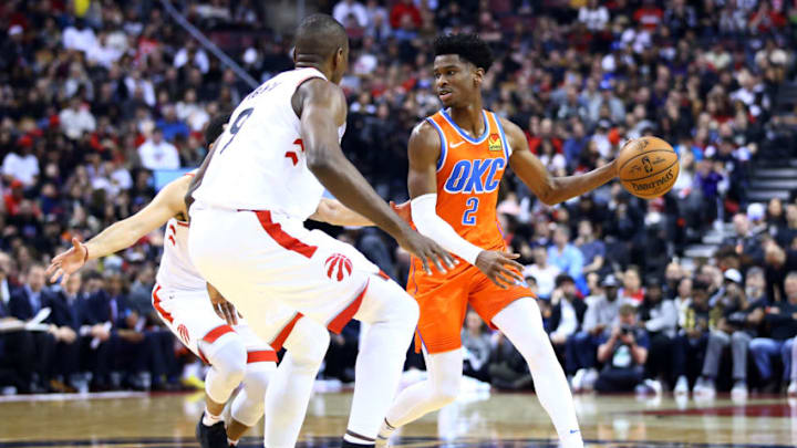 Shai Gilgeous-Alexander #2 of the OKC City Thunder dribbles the ball as Serge Ibaka #9 and Fred VanVleet #23 of the Toronto Raptors defends during the second half of an NBA game at Scotiabank Arena on December 29, 2019 in Toronto.. (Photo by Vaughn Ridley/Getty Images)