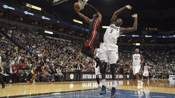 Dec 7, 2013; Minneapolis, MN, USA; Miami Heat shooting guard Dwyane Wade (3) goes up for a dunk past Minnesota Timberwolves center Gorgui Dieng (5) in the first half at Target Center. Mandatory Credit: Jesse Johnson-USA TODAY Sports