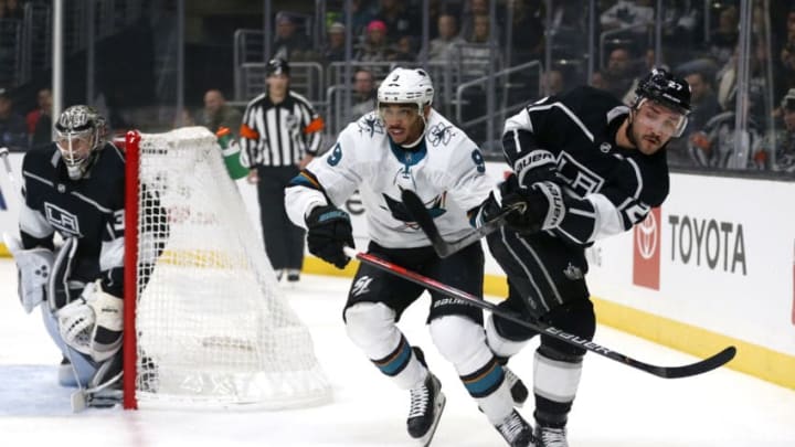 LOS ANGELES, CALIFORNIA - NOVEMBER 25: Alec Martinez #27 of the Los Angeles Kings passes the puck as Evander Kane #9 of the San Jose Sharks defends during the first period at Staples Center on November 25, 2019 in Los Angeles, California. (Photo by Katharine Lotze/Getty Images)