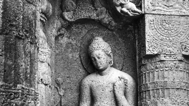 A stone sculpture of the Buddha begging for alms in the Ajanta caves, in the Aurangabad District of Maharashtra, India, 1940s. They date from the 2nd century BCE. (Photo by Dinodia Photos/Getty Images)