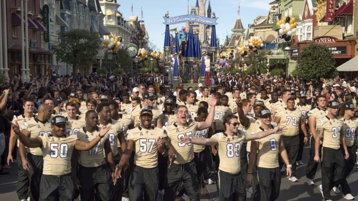 LAKE BUENA VISTA, FL – JANUARY 12: In this handout photo provided by Disney Parks, University of Central Florida football players wave to fans at the Magic Kingdom park during a gala parade in their honor January 12, 2014 in Lake Buena Vista, Florida. The UCF football team finished the 2013 season ranked 10th in national polls following a Cinderella-story victory over the Baylor Bears in the Tostitos Fiesta Bowl on January 1, 2014. The Magic Kingdom is one of four theme parks at the Walt Disney World Resort in Lake Buena Vista, Florida. (Photo by Kent Phillips/Disney Parks via Getty Images)