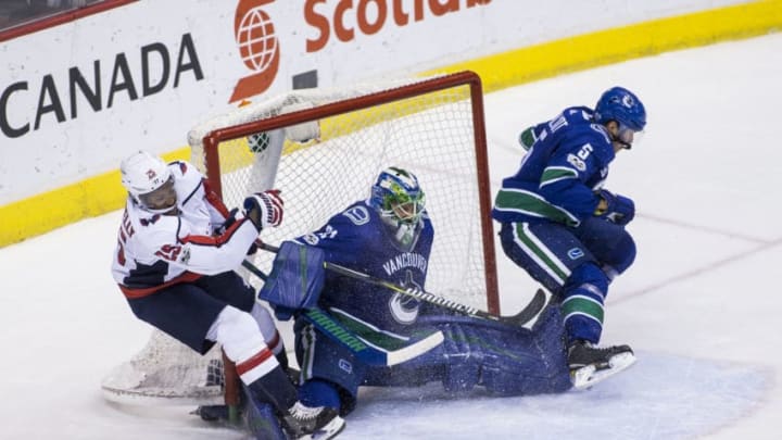 VANCOUVER, BC - OCTOBER 26: Vancouver Canucks Defenceman Derrick Pouliot (5) checks Washington Capitals Right Wing Devante Smith-Pelly (25) into Vancouver Canucks Goalie Anders Nilsson (31) during the second period of a NHL hockey game on October 26, 2017, at Rogers Arena in Vancouver, BC. (Photo by Bob Frid/Icon Sportswire via Getty Images)