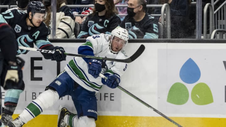 Jan 1, 2022; Seattle, Washington, USA; Vancouver Canucks center J.T. Miller (9) passes the puck as Seattle Kraken center Yanni Gourde(37) defends during the first period at Climate Pledge Arena. Mandatory Credit: Stephen Brashear-USA TODAY Sports
