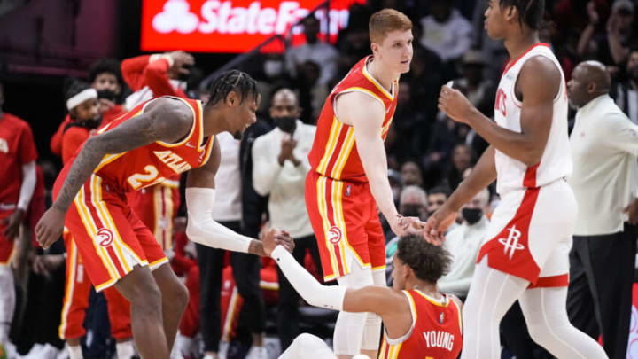 Dec 13, 2021; Atlanta, Georgia, USA; Atlanta Hawks guard Trae Young (11) is helped up by forward Cam Reddish (22) and guard Kevin Huerter (3) after being fouled against the Houston Rockets during the first half at State Farm Arena. Mandatory Credit: Dale Zanine-USA TODAY Sports