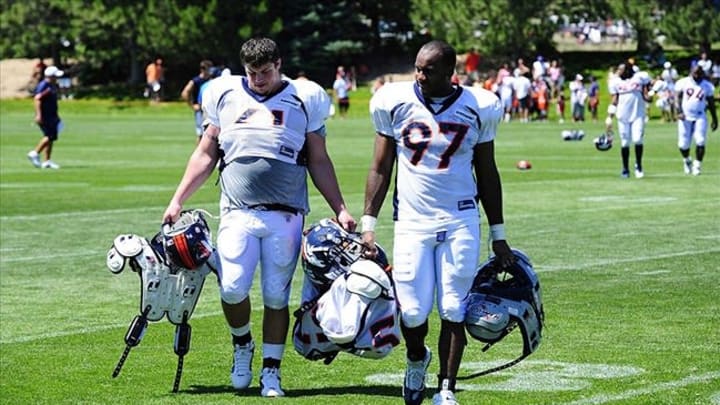 July 30, 2011; Englewood, CO, USA; Denver Broncos defensive tackle Colby Whitlock (61) and defensive end Jeremy Beal (97) walk with the pads of others players following the end of training camp drills at the Broncos Training Facility. Mandatory Credit: Ron Chenoy-USA TODAY Sports