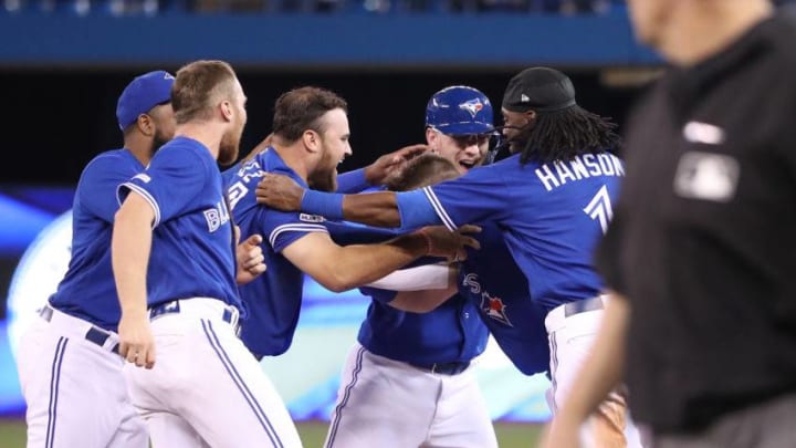 Justin Smoak #14 of the Toronto Blue Jays is congratulated by teammates after driving in the game-winning run with an RBI single in the eleventh inning during MLB game action. (Photo by Tom Szczerbowski/Getty Images)