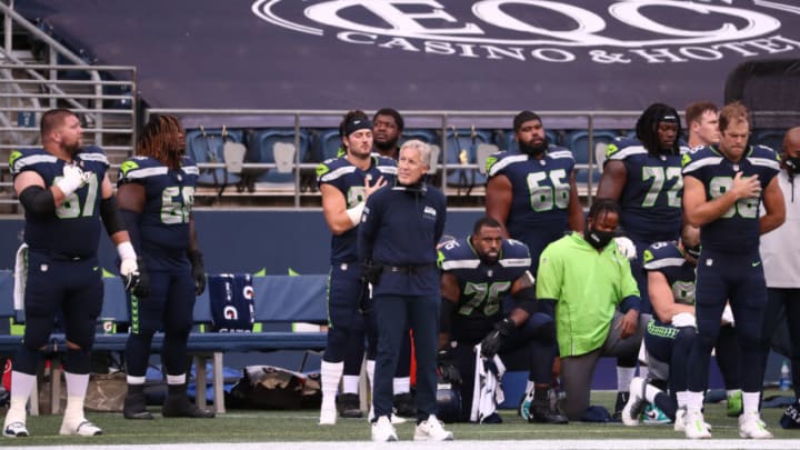SEATTLE, WASHINGTON - SEPTEMBER 20: Seattle Seahawks coaches and players stand or kneel during the national anthem before the game against the New England Patriots at CenturyLink Field on September 20, 2020 in Seattle, Washington. (Photo by Abbie Parr/Getty Images)