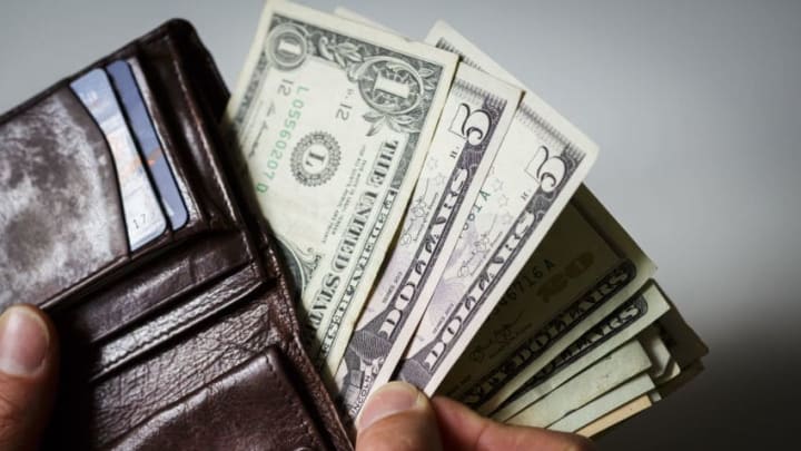 BERLIN, GERMANY – JUNE 03: A man hold a wallet, filled with Dollar bills on June 03, 2015, in Berlin, Germany. (Photo by Thomas Trutschel/Photothek via Getty Images)