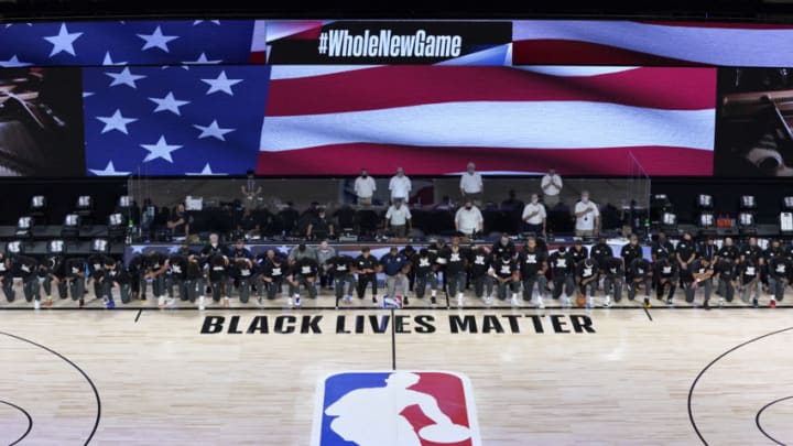 LAKE BUENA VISTA, FLORIDA - JULY 30: Members of the New Orleans Pelicans and Utah Jazz kneel before a Black Lives Matter logo before the start of their game at HP Field House at ESPN Wide World Of Sports Complex on July 30, 2020 in Reunion, Florida. NOTE TO USER: User expressly acknowledges and agrees that, by downloading and or using this photograph, User is consenting to the terms and conditions of the Getty Images License Agreement. (Photo by Pool/Getty Images)