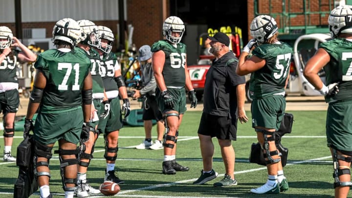 Michigan State’s offensive line coach Chris Kapilovic, center, talks with players during the opening day of MSU’s football fall camp on Thursday, Aug. 3, 2023, in East Lansing.