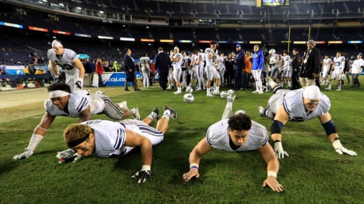 SAN DIEGO, CA - DECEMBER 21: Andrew Eide #79, Sione Takitaki #16, Sae Tautu #31 and Algernon Brown #24 of the Brigham Young Cougars slide on the turf after defeating the Wyoming Cowboys 24-21 to win the Poinsettia Bowl in a game on December 21, 2016 in San Diego, California. (Photo by Sean M. Haffey/Getty Images)