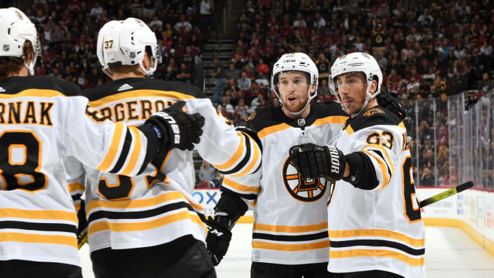 GLENDALE, ARIZONA – OCTOBER 05: Brad Marchand #63 of the Boston Bruins is congratulated by teammate Matt Grzelcyk #48 after his goal against the Arizona Coyotes as David Pastrnak #88 and Patrice Bergeron #37 of the Bruins skate in during the first period at Gila River Arena on October 05, 2019 in Glendale, Arizona. (Photo by Norm Hall/NHLI via Getty Images)
