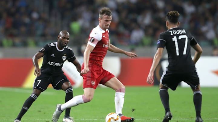 BAKU, AZERBAIJAN - OCTOBER 04: Rob Holding of Arsenal passes the ball under pressure from Innocent Emeghara and Abdellah Zoubir of Qarabag during the UEFA Europa League Group E match between Qarabag FK and Arsenal at on October 4, 2018 in Baku, Azerbaijan. (Photo by Francois Nel/Getty Images)