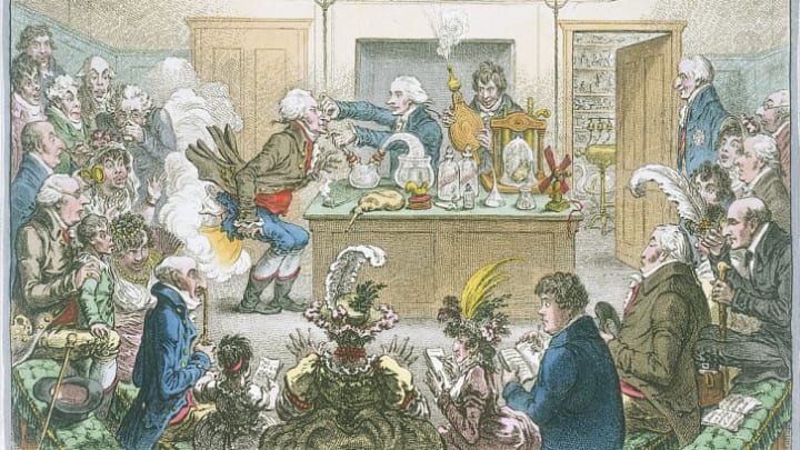 A 19th-century illustration satirizes Humphry Davy's experiments with nitrous oxide. Davy operates the bellows filled with laughing gas, which flows through a tube in his assistant's mouth, resulting in the gas exploding out of his bum.