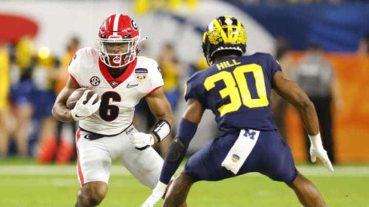 MIAMI GARDENS, FLORIDA – DECEMBER 31: Kenny McIntosh #6 of the Georgia Bulldogs runs with the ball as Daxton Hill #30 of the Michigan Wolverines defends in the second quarter of the game in the Capital One Orange Bowl for the College Football Playoff semifinal game at Hard Rock Stadium on December 31, 2021 in Miami Gardens, Florida. (Photo by Michael Reaves/Getty Images)