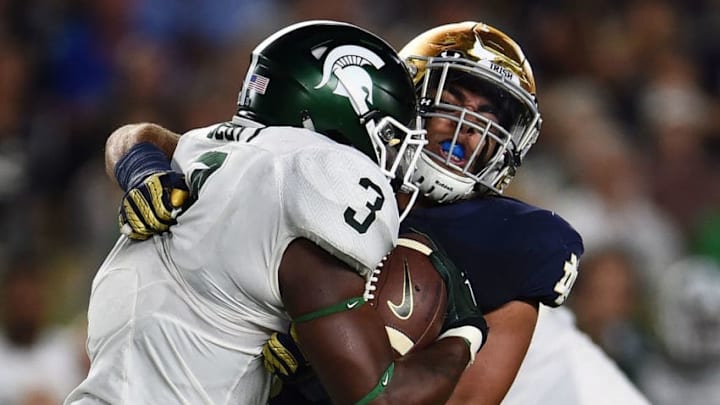 SOUTH BEND, IN - SEPTEMBER 17: LJ Scott #3 of the Michigan State Spartans is brought down by James Onwualu #17 of the Notre Dame Fighting Irish during a game at Notre Dame Stadium on September 17, 2016 in South Bend, Indiana. Michigan State defeated Notre Dame 36-28. (Photo by Stacy Revere/Getty Images)