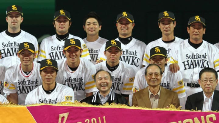 In a picture taken on November 20, 2011, Pacific League champions Softbank Hawks (first row L-R) manager Koji Akiyama, owner Masayoshi Son and chairman Sadaharu Oh smile with their players as they hold a large pennant to celebrate victory of the Japan Series professional baseball championship in Fukuoka, western Japan. The Hawks defeated Central League champion Chunichi Dragons 3-0 and clinched the Japan Series title 4-3. AFP PHOTO / JIJI PRESS (Photo by JIJI PRESS / JIJI PRESS / AFP) / Japan OUT (Photo credit should read JIJI PRESS/AFP via Getty Images)