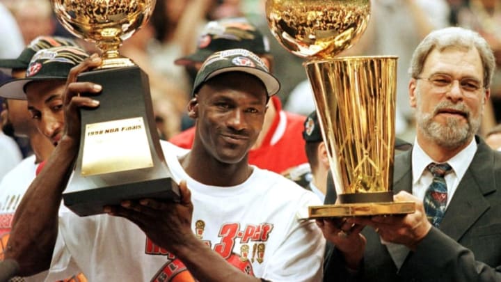 SALT LAKE CITY, UNITED STATES: In this 14 June 1998 file photo, Michael Jordan (L) holds the NBA Finals Most Valuable Player trophy and former Chicago Bulls head coach Phil Jackson holds the NBA champions Larry O'Brian trophy 14 June after winning game six of the NBA Finals with the Utah Jazz at the Delta Center in Salt Lake City, UT. The Bulls won the game 87-86 to take their sixth NBA championship. Jackson left the Bulls following the 1998 season and 12 January reports indicate that Jordan plans to announce his retirement at a 13 January news conference in Chicago. AFP PHOTO/FILES/Jeff HAYNES (Photo credit should read JEFF HAYNES/AFP/Getty Images)