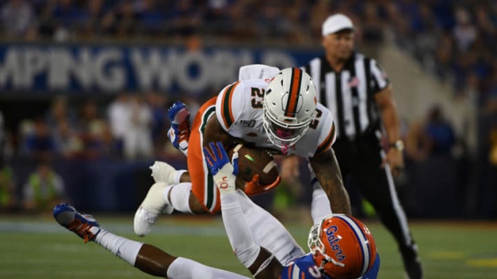 ORLANDO, FL - AUGUST 24: Cam'Ron Harris #23 of the Miami Hurricanes runs over Ventrell Miller #51 of the Florida Gators during the first half of the Camping World Kickoff at Camping World Stadium on August 24, 2019 in Orlando, Florida.(Photo by Mark Brown/Getty Images)