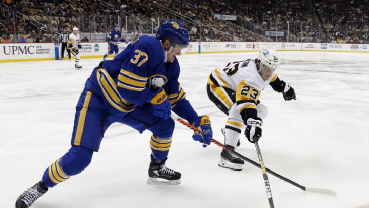 Dec 10, 2022; Pittsburgh, Pennsylvania, USA; Buffalo Sabres center Casey Mittelstadt (37) and Pittsburgh Penguins left wing Brock McGinn (23) reach for the puck during the second period at PPG Paints Arena. Mandatory Credit: Charles LeClaire-USA TODAY Sports