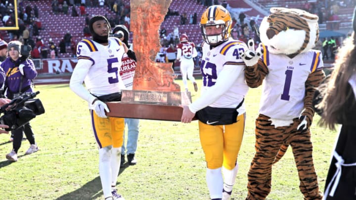 Nov 12, 2022; Fayetteville, Arkansas, USA; LSU Tigers safety Jay Ward and defensive end Lane Blue (42) carry The Boot trophy after the game against the Arkansas Razorbacks at Donald W. Reynolds Razorback Stadium. LSU won 13-10. Mandatory Credit: Nelson Chenault-USA TODAY Sports