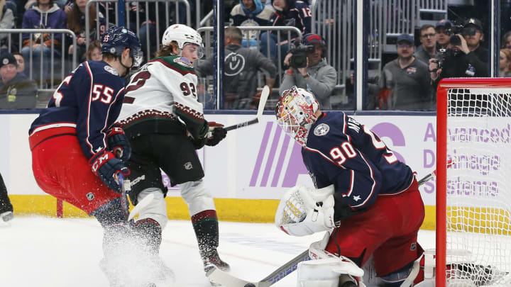 Nov 16, 2023; Columbus, Ohio, USA; Columbus Blue Jackets goalie Elvis Merzlikins (90) stops the tip shot from Arizona Coyotes center Logan Cooley (92) during the third period at Nationwide Arena. Mandatory Credit: Russell LaBounty-USA TODAY Sports