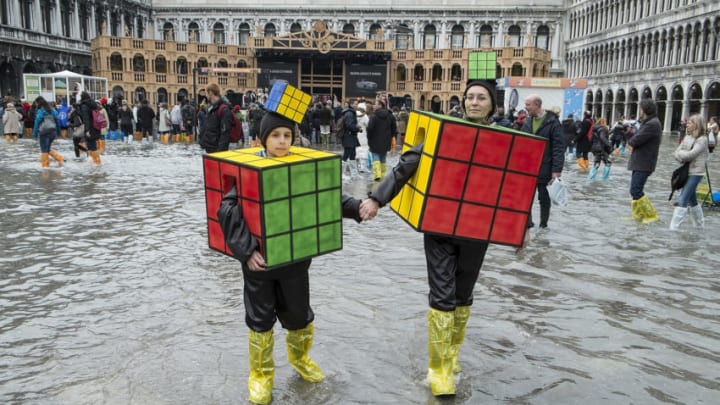 VENICE, ITALY - MARCH 04: A mother and son wearing carnival costumes walk in flooded Saint Mark's Square on the last day of Carnival on March 4, 2014 in Venice, Italy. It is the last day of the 2014 Carnival of Venice which has run from February 15 and includes a program of gala dinners, parades, dances, masked balls and music events. High water has been forecast for the final day with the chance of possible flooding. (Photo by Marco Secchi/Getty Images)