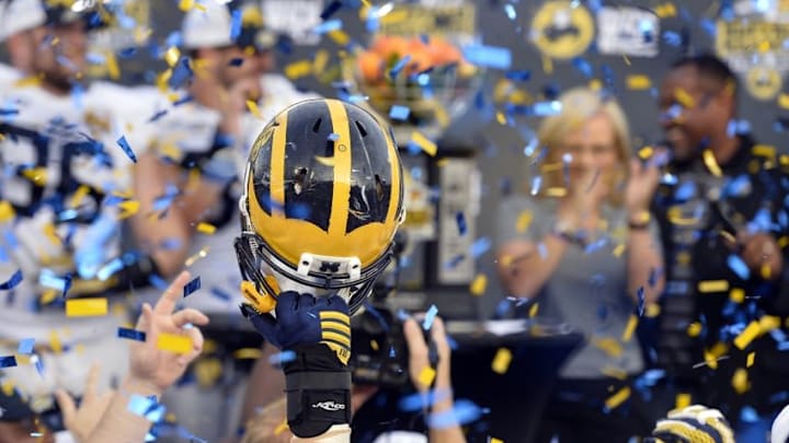 Jan 1, 2016; Orlando, FL, USA; Michigan Wolverines player raises his helmet during the celebration of defeating Florida Gators 41-7 to earn the 2016 Citrus Bowl championship at Orlando Citrus Bowl Stadium. Michigan Wolverines defeated Florida Gators 41-7. Mandatory Credit: Tommy Gilligan-USA TODAY Sports