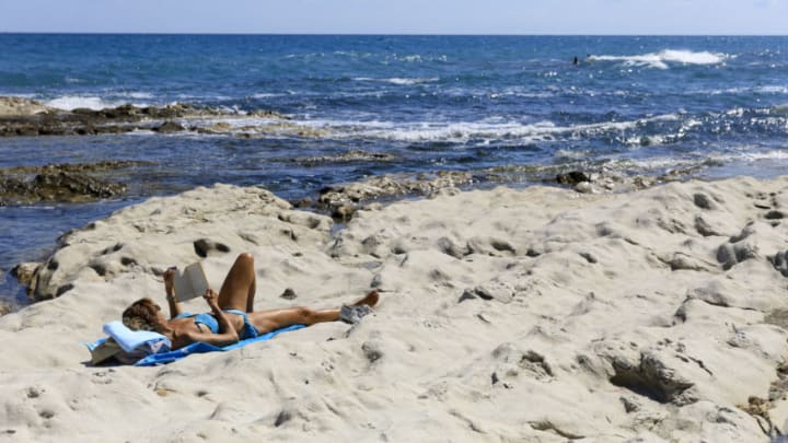 ANCONA, MARCHE, ITALY - AUGUST 28: A woman is reading a book while sunbathing on the beach, on August 28, 2020 in Ancona, Italy. (Photo by Thierry Monasse/Getty Images)