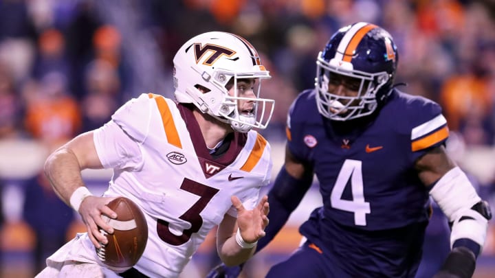 CHARLOTTESVILLE, VA – NOVEMBER 27: Braxton Burmeister #3 of the Virginia Tech Hokies scrambles past Elliott Brown #4 of the Virginia Cavaliers in the first half during a game at Scott Stadium on November 27, 2021 in Charlottesville, Virginia. (Photo by Ryan M. Kelly/Getty Images)